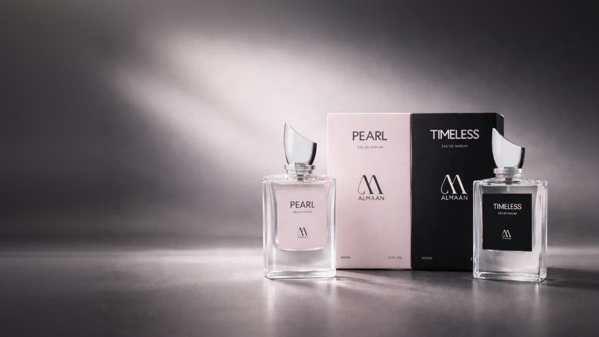 Two Almaan perfume bottles, 'Pearl' and 'Timeless', with their packaging on a reflective surface.